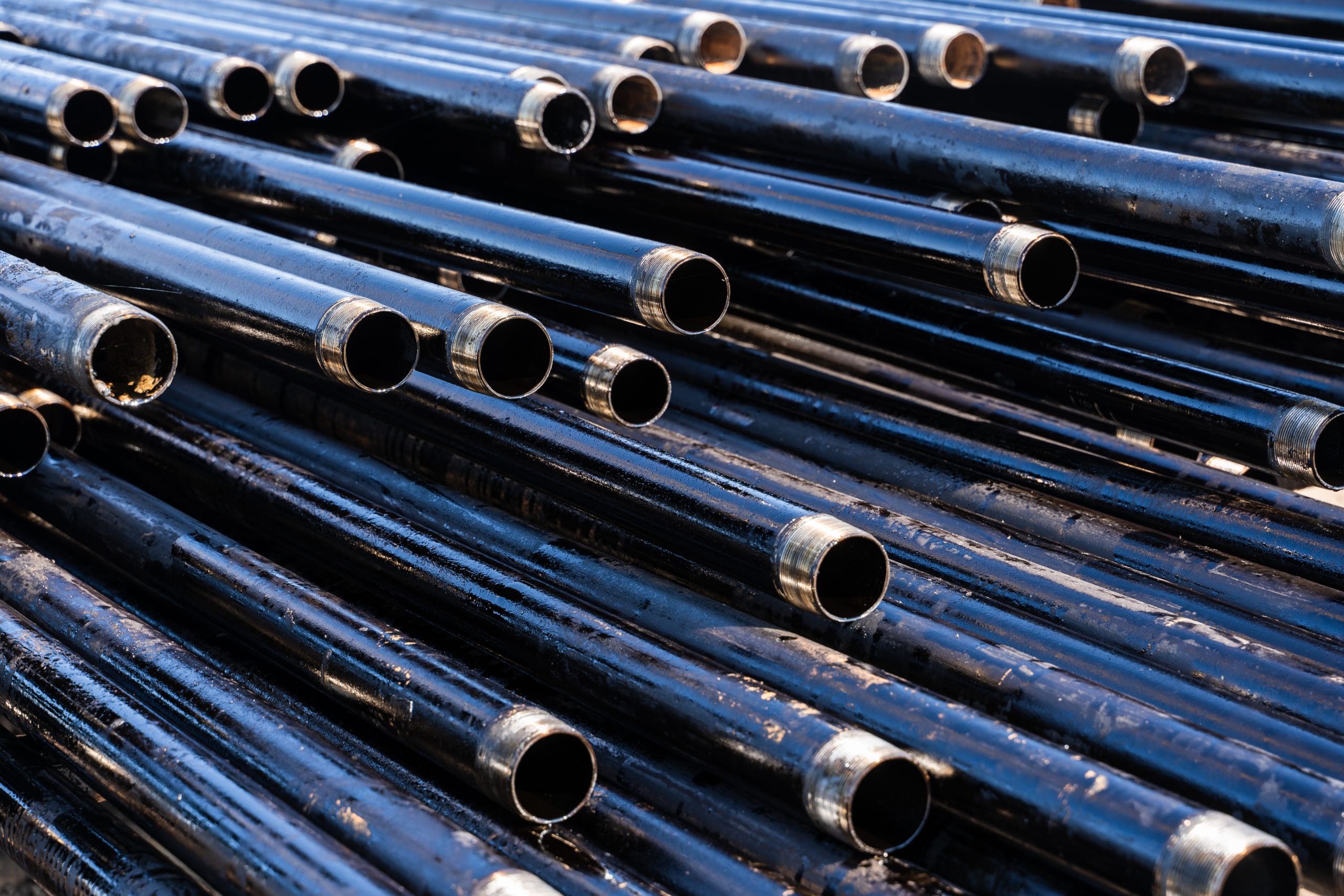 Pipe for Drilling rigs for oil and gas on background. Drilling of oil and gas wells. Drill pipe. Tubing for oil and gas listed on the pedestal out of the wells after washing and ready for inspection.